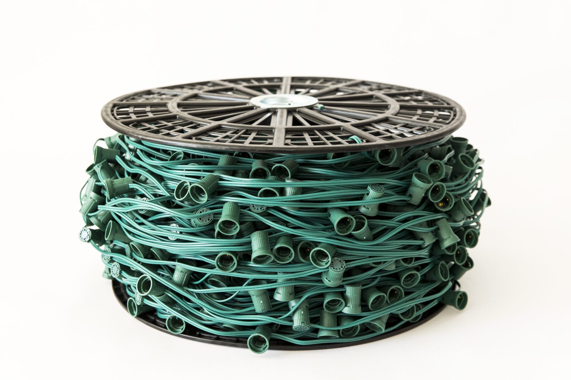 A coiled bundle of green outdoor string lights with empty plastic sockets